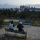 People sit on a hill overlooking Dodger Stadium and downtown Los Angeles on March 26, 2020.